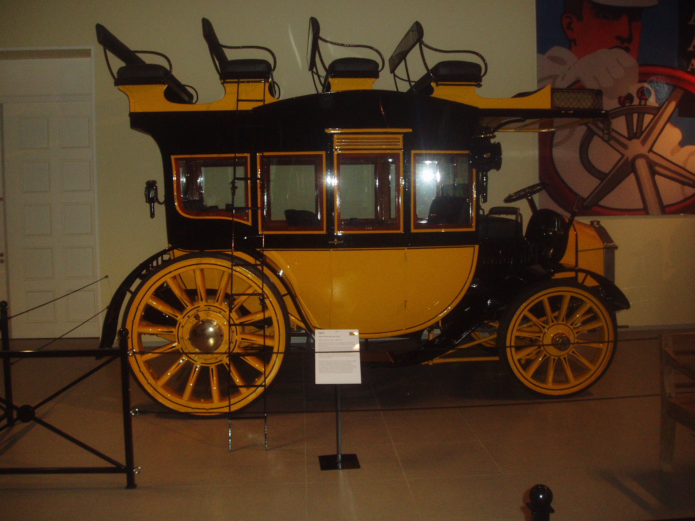 Geel-zwarte historische postkoets op museumvloer